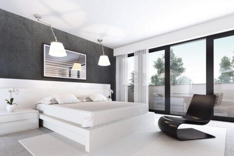 Grey wall paneling with textured velvet panels behind white bed