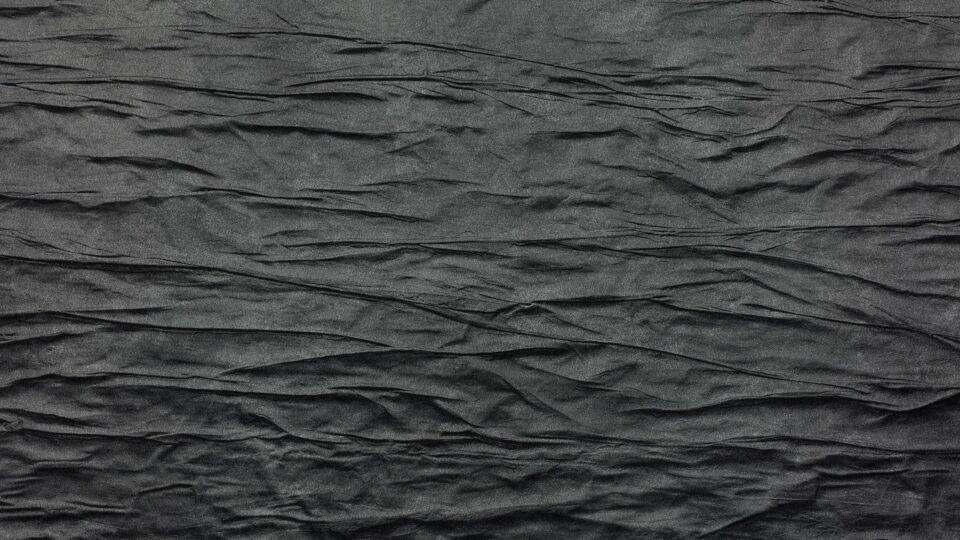 Detailaufnahme einer schwarzen und strukturierten Oberfläche im Knitter-Look