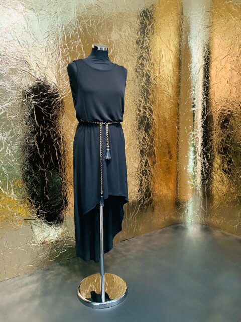 Schaufensterpuppe vor goldener, spiegelnder Designplatte mit ausgeprägte Struktur