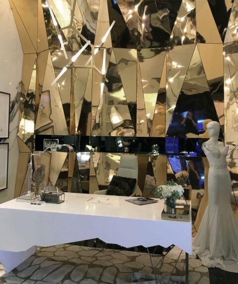 Wall in shiny gold decor with single triangular shapes, white desk in front of it