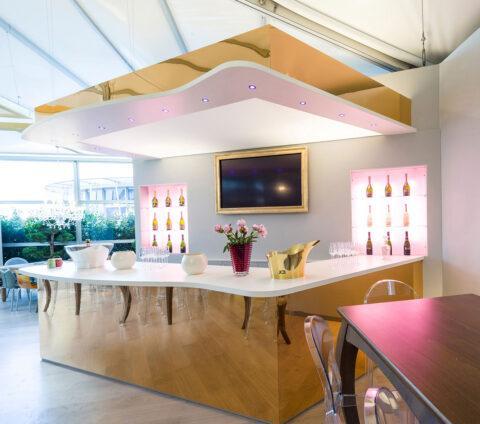 Moderne Wein-Bar mit goldfarbenem spiegelndem Pult und rosa Beleuchtung