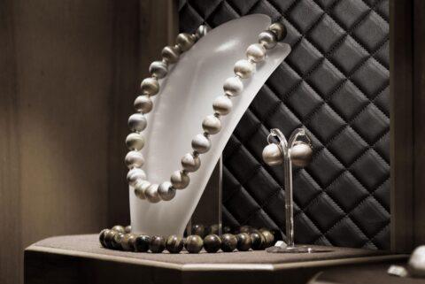 Detail of a wooden chain on a jewelry stand against a black leather look background