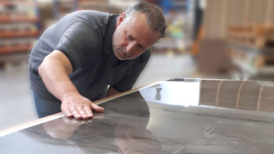 Man bending over decorative panel checking for defects