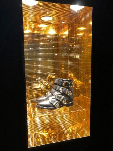 Shop window dressed in gold, inside a pair of black boots