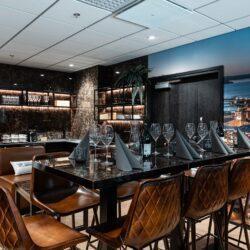Bar in noble, high-gloss look with brown leather bar stools