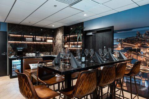 Bar in noble, high-gloss look with brown leather bar stools