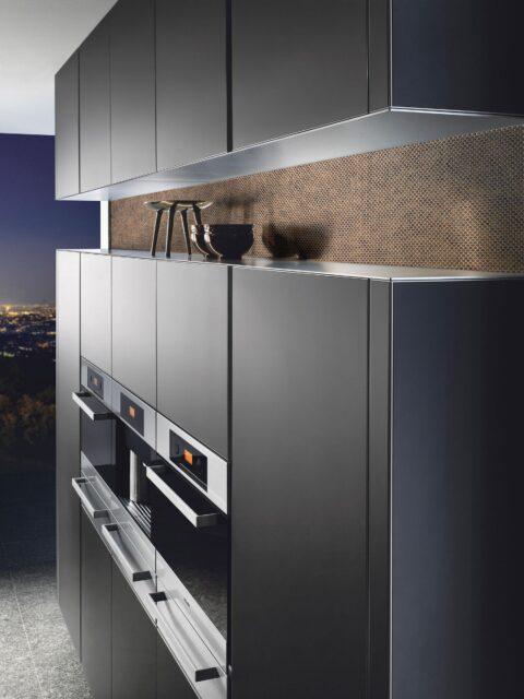 Black kitchen front with small niche in bronze at eye level