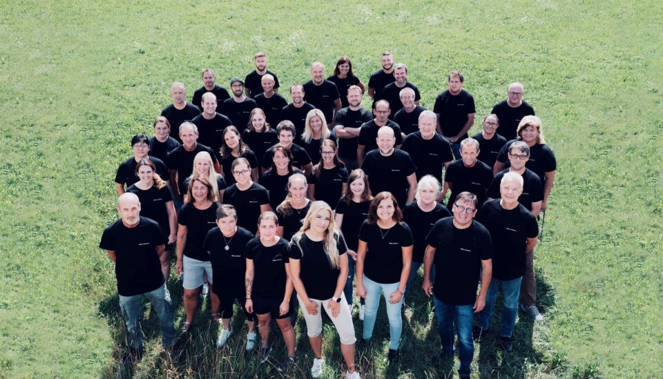 SIBU DESIGN team photo, all laughing and wearing black t-shirt and standing in a group on the green field