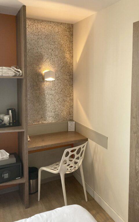 Alcove with golden patterned wall panel with small desk and white armchair