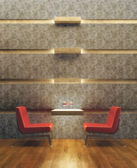 Two red chairs in front of a wall with light gray, patterned design panels and golden elements