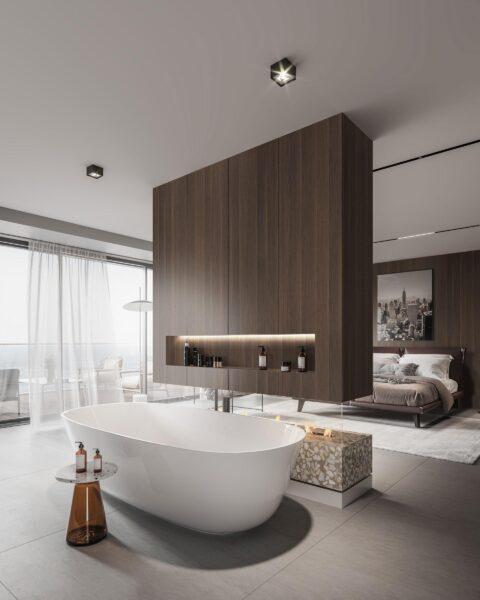 Offenes Bad mit freistehender Badewanne und Schlafzimmer mit einer dunklen Holzwand mit integriertem Kamin abgetrennt