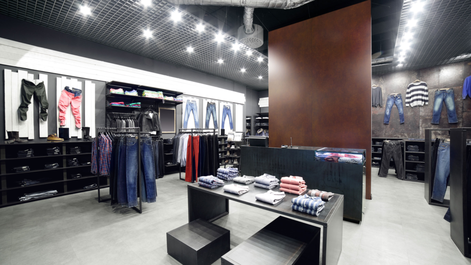 Clothing shop with dark furnishings and panel in dark wood look in the centre