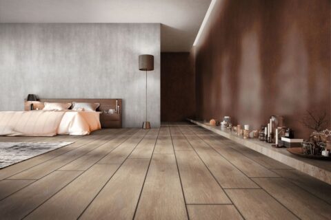 Schlafzimmer mit dunklem Holzboden und einer Wand mit Paneelen in rötlicher Holzoptik