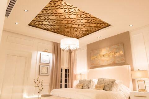 Helles Schlafzimmer mit Ornamentdecke und Goldener Designplatte