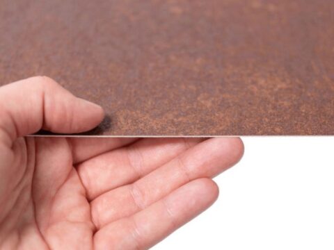 Hand mit einer Dekorplatte in rötlicher Holzoptik