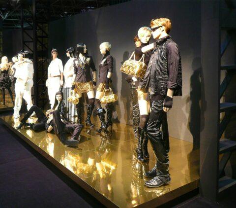 Shopwindow mit Schaufensterpuppen auf einem spiegelndem goldenem Podest