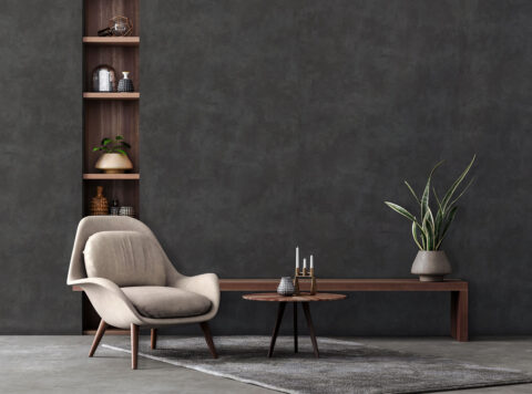 Gray mottled wall panels, a chair in front of it in cream and a small table