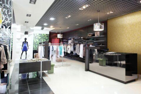 Modegeschäft mit spiegelndem Tresen und goldenen Dekorplatten im Hintergrund