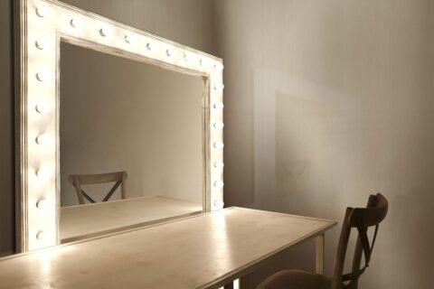 großer beleuchteter Spiegel mit gebürsteten cremefarbenen Wandpaneelen im Hintergrund