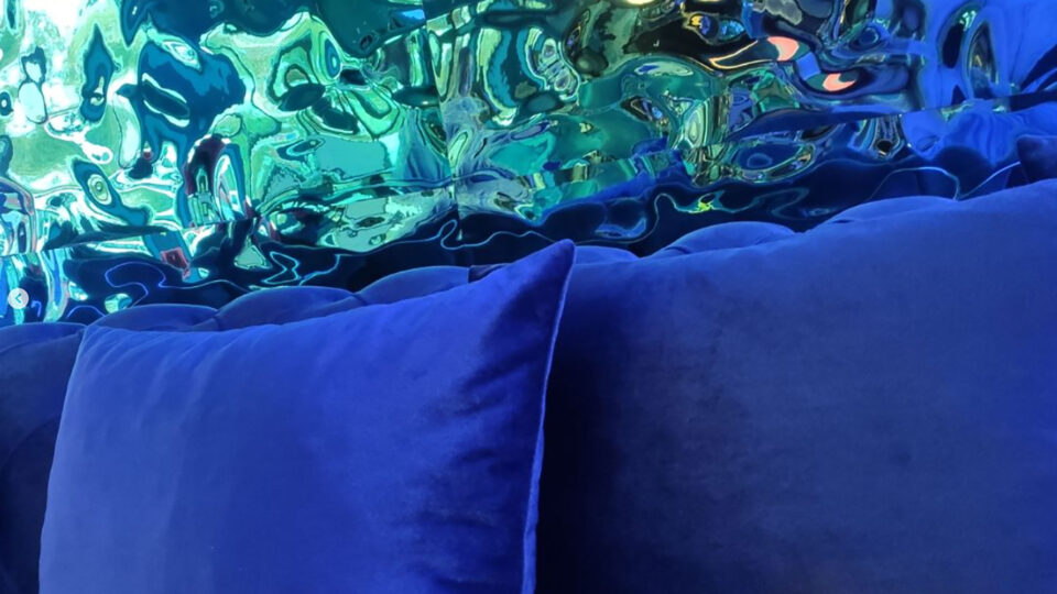 blue/green mirror wall in the background, blue upholstery in the foreground