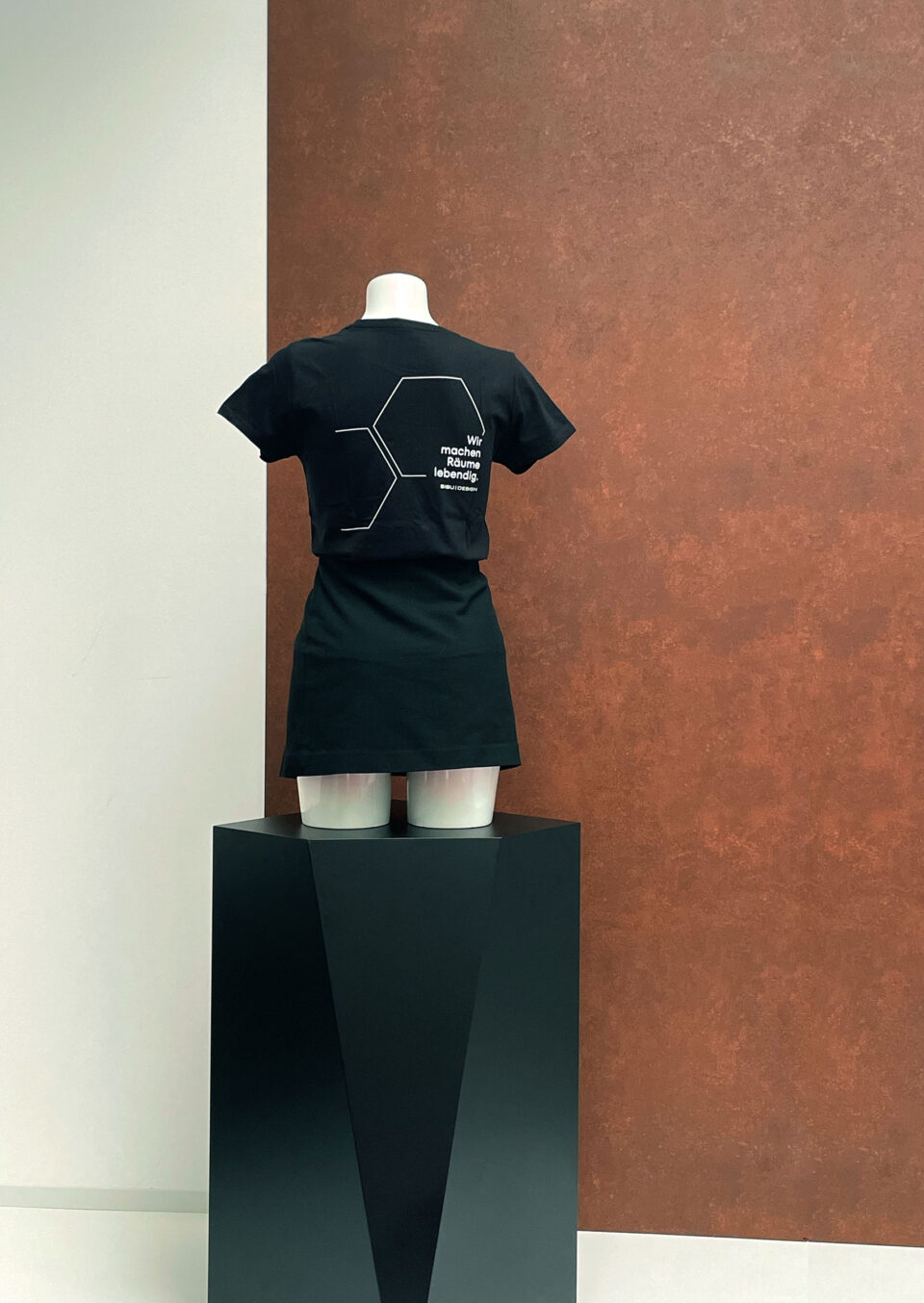 schwarz gekleidete Schaufensterpuppe vor rostigem Hintergrund