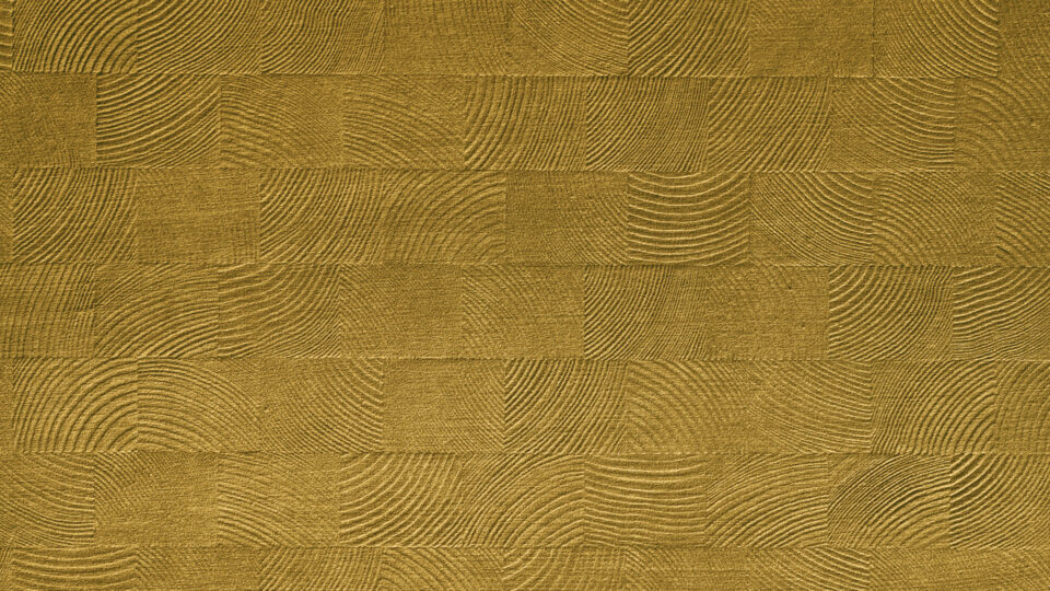 Detailaufnahme eines Designpaneels, dessen Struktur Holzmosaiken ähnelt. Das Oberflächenmaterial des Designs ist konträr aus weichem goldene, leicht schimmernden Samt und verleiht der Struktur einen besonders edlen Charakter.