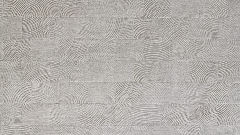 Detailaufnahme eines Designpaneels, dessen Struktur Holzmosaiken ähnelt. Das Oberflächenmaterial des Designs ist konträr aus weichem hellgrauen, leicht schimmernden Samt und verleiht der Struktur einen besonders edlen Charakter.