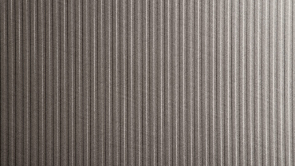 Detailaufnahme einer Dekorplatte dessen Design eine strukturierte vertikale Linienführung zeigt. Edle schmale Streifen, die sowohl in den Höhen als auch in den Tiefen gleichmäßig sind. Die Oberfläche stellt ein metallisches stählernes Kunstleder dar.