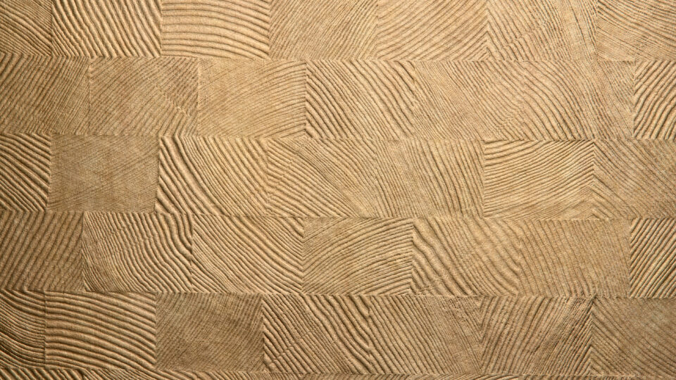 Detailaufnahme eines Designpaneels, dessen Struktur Holzmosaiken ähnelt. Das Oberflächenmaterial des Designs erinnert an helles bronzefarbenes Metall.