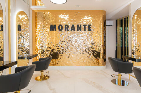 moderner, sehr heller Friseursalon mit golden schimmernder Wand als Blickfang