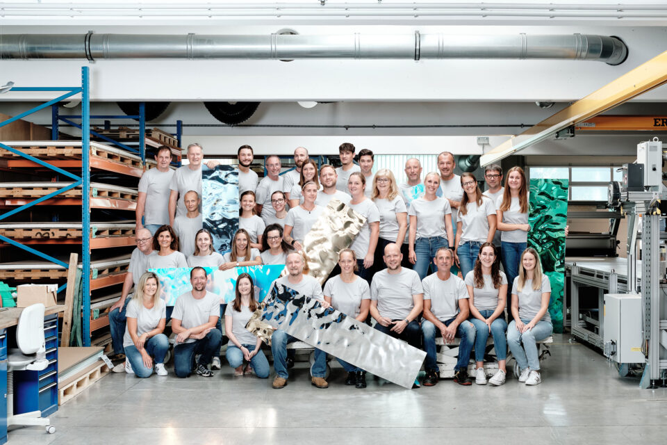 Mitarbeitergruppenfoto im Hintergrund die Produktionshalle