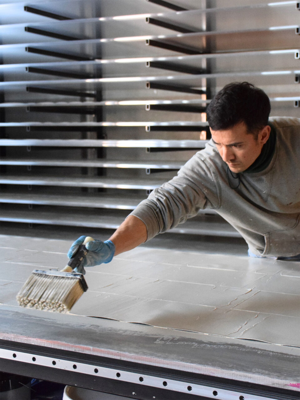 Mann bringt Farbe auf die Tapete mit einem groben Pinsel