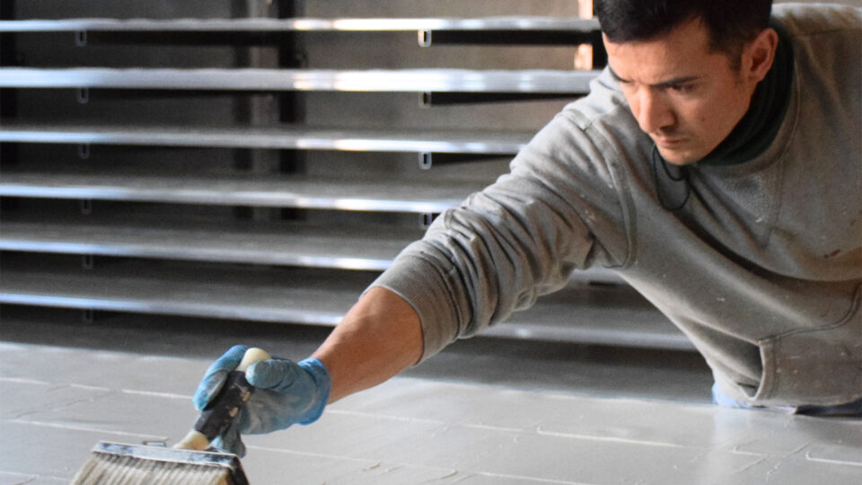 Mann bringt Farbe auf die Tapete mit einem groben Pinsel