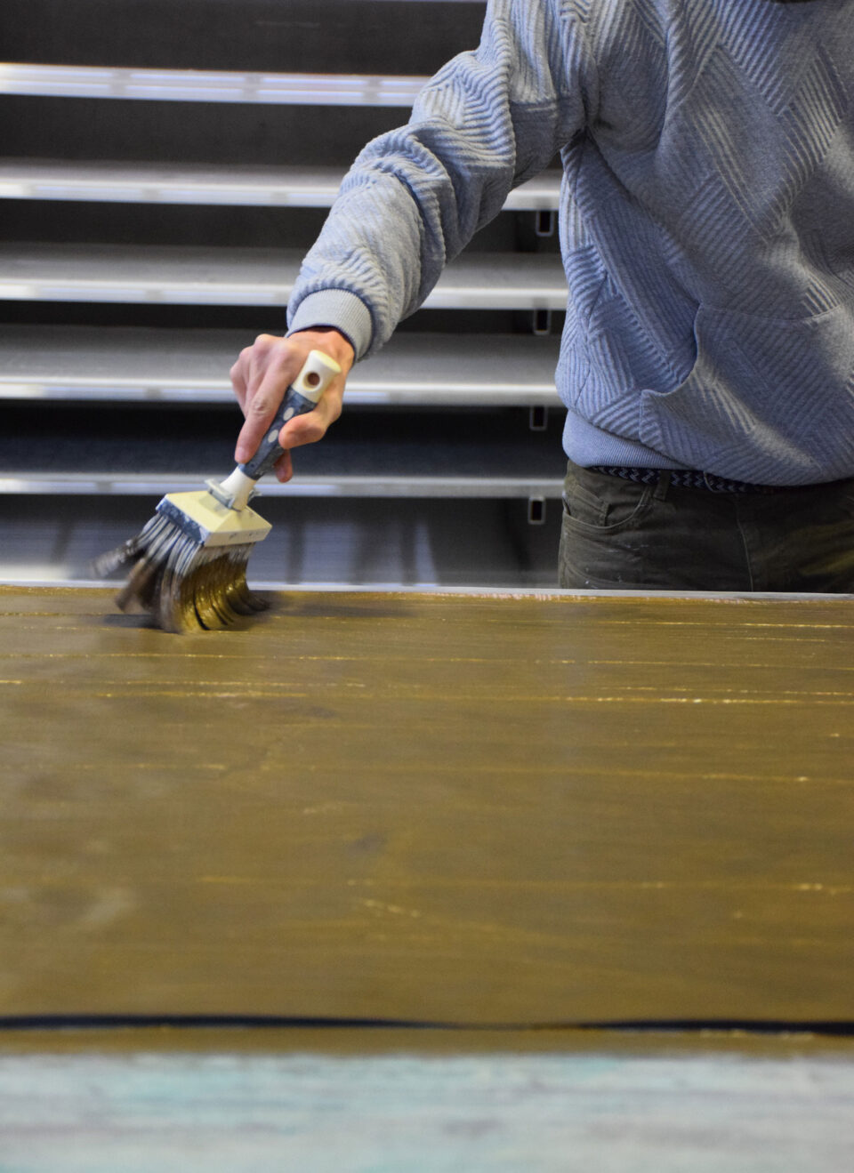 Mit einem Pinsel trägt ein Herr goldene Farbpigmente auf die Wandbeläge auf