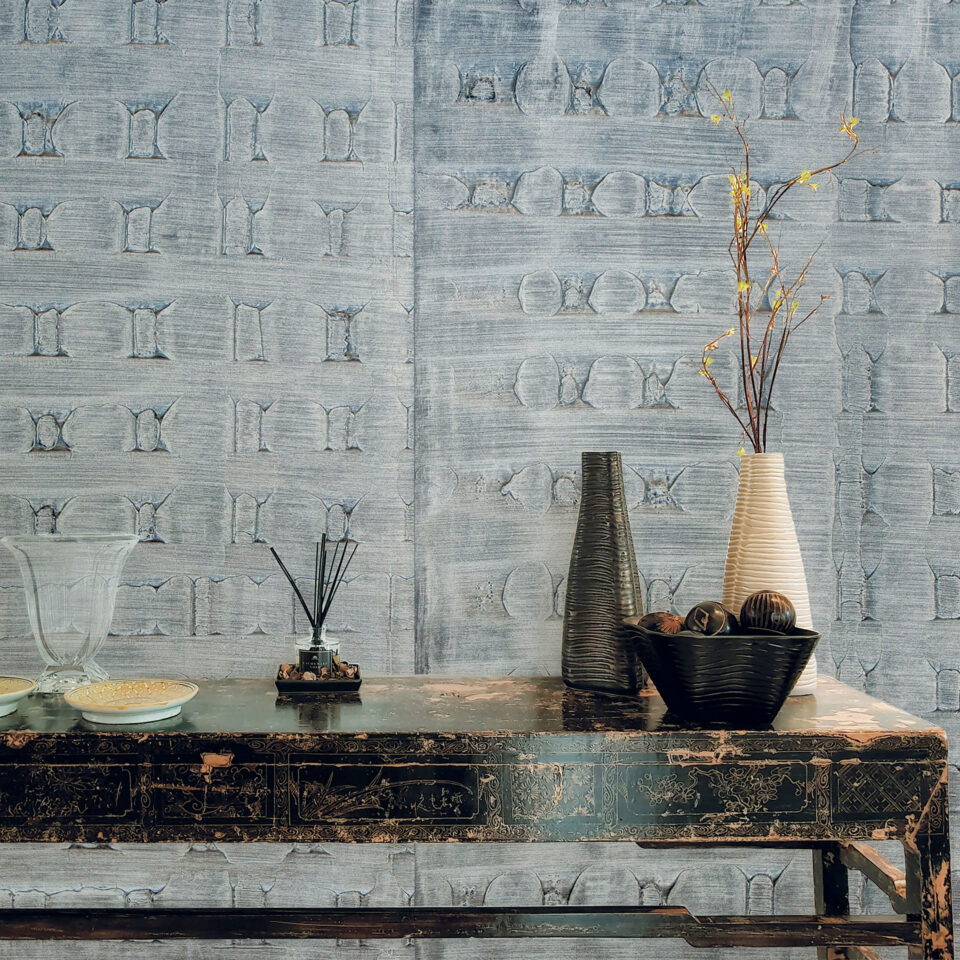 Modern dekorierter Tisch vor einer grauen stark strukturierten Wandverkleidung