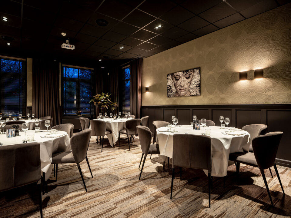 Restaurantumgebung mit elegant gedeckten runden Tischen. Im Hintergrund eine Tapete mit Kreisformen die elegant ineinander laufen.