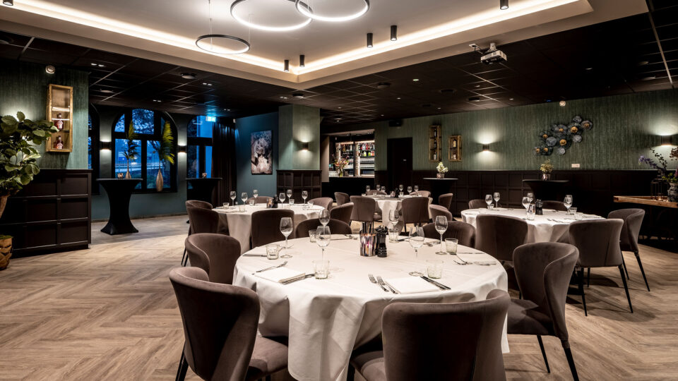 Restaurantumgebung mit elegant gedeckten runden Tischen. Im Hintergrund eine Tapete in graugrünen Tönen die in vertikalen auffälligen Linien verläuft