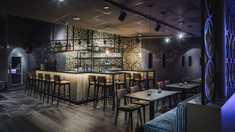 Ein Barbereich der auffällige Tapeten kombiniert, die im Scheinwerferlicht schimmernde Effekte widerspiegeln,