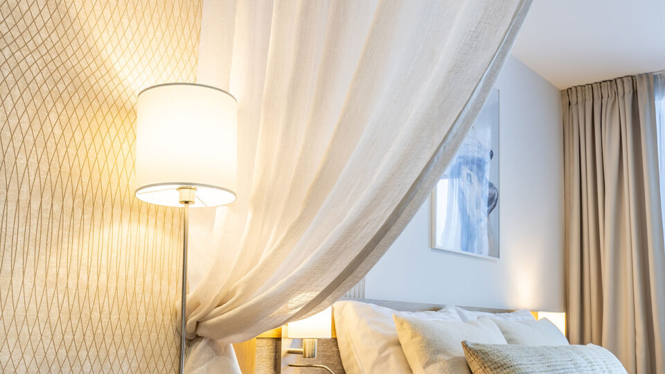 Ein Hotelzimmer, dessen WAnd durch eine Tapete verkleidet wurde die mit feinen Linien geometrische Figuren abbildet.