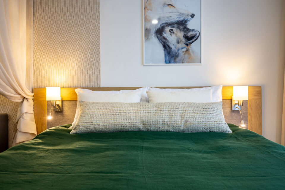 Ein Hotelzimmer, dessen linker Wandbereich durch eine Tapete verkleidet wurde die mit feinen Linien geometrische Figuren abbildet.