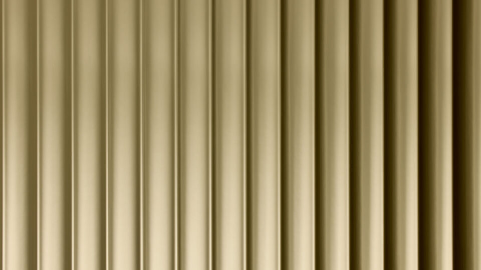 A close-up of a design panel, characterized by wide vertically running lines. The surface is reflective with a gold tone. The varying heights and depths of the structure create a particularly deep effect that fascinates.