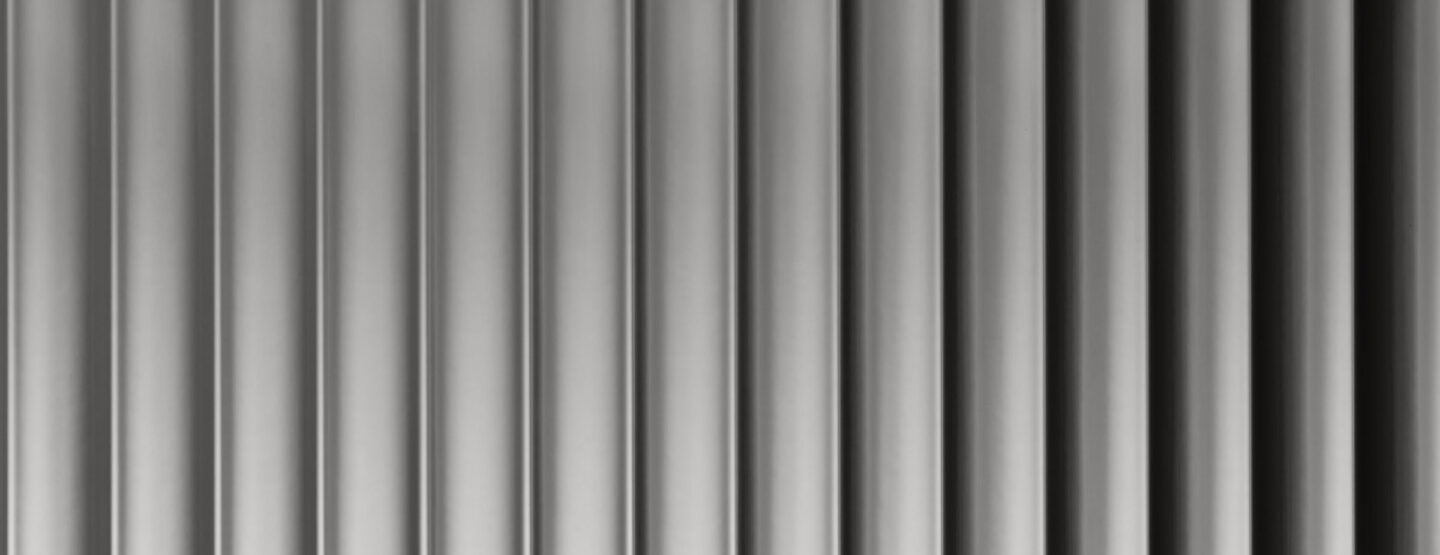 A close-up of a design panel, characterized by wide vertically running lines. The surface is reflective with a silver tone. The varying heights and depths of the structure create a particularly deep effect that captivates.