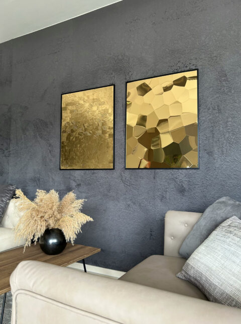 Two couches facing each other, a table with shrubs in a black round vase in the center. In the background, two gold-framed SIBU | DESIGN panels.