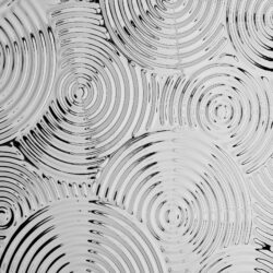 Detailaufnahme eines strukturierten Designpaneels. Die Struktur zeigt verschieden große Kreise die sich hintereinander zeigen und in sich immer kleinere Kreise beinhalten, Die Oberfläche ist spiegelnd und glänzt im Licht. Die Farbe ist Silber.