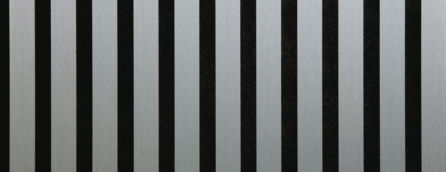 Detailaufnahme eines schallabsorbierenden Akustikpaneels. Die Oberfläche ist schwarz und wird von edlen, silbernen Streifen im gebürsteten Look durchzogen.