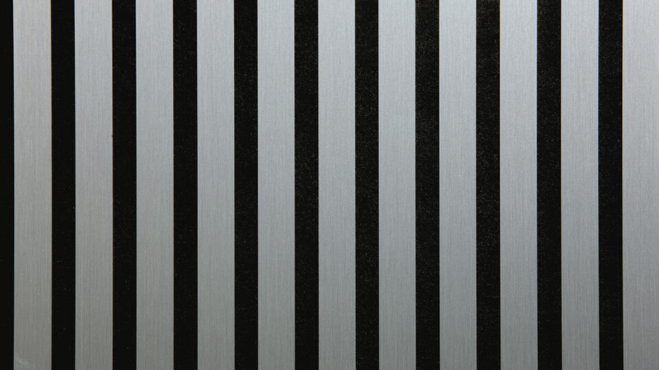 Detailed shot of a sound-absorbing acoustic panel. The surface is black and features elegant, brushed-silver stripes.