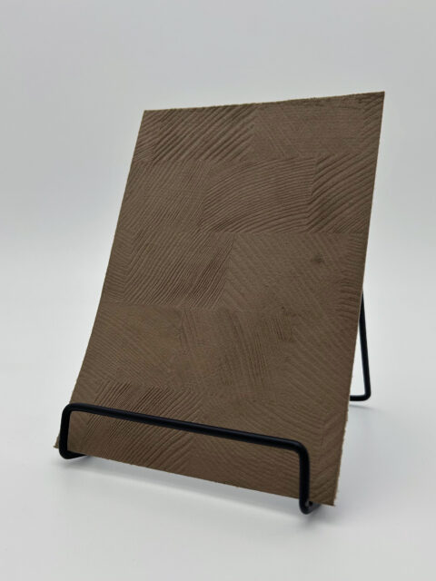 Display stand with a velvet mocha-colored design panel with a structured checkered pattern.