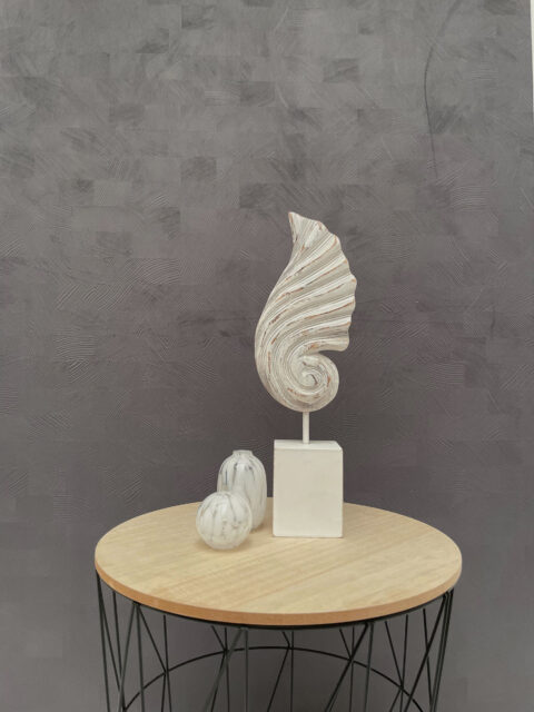 Two white vases next to a shell sculpture. In the background, a grayish design panel with a textured checkered pattern.