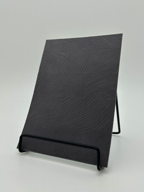 Display stand with a grayish design panel with a checkered texture. The surface is made of velvet.