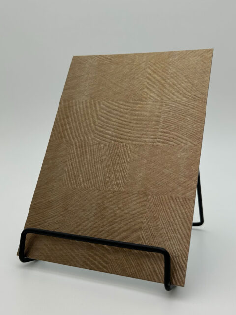 Display stand with a sandy-metallic design panel made of faux leather. The structure is structured checkered.